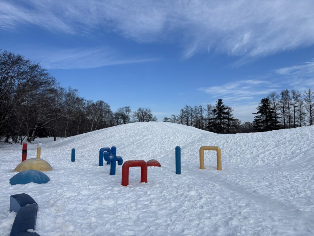 児童遊園エリアの丘。雪で白く覆われていて、十勝晴れの青空が広がる。